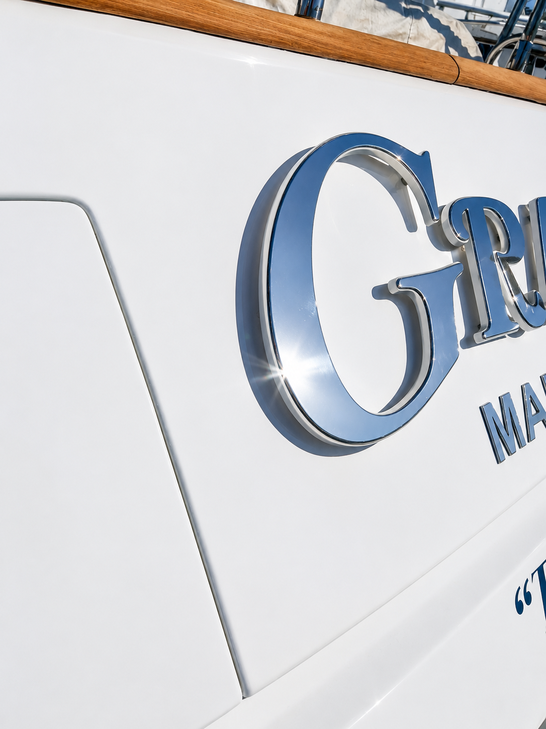 Polished stainless steel yacht lettering detail on a white hull